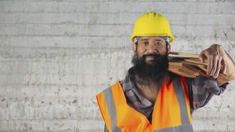 Trabalhador carregando tábuas em obra